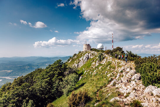 View of a stone building perched atop a grassy, rocky peak under a sky of scattered clouds and blue, beckoning exploration, Mala Ucka, Primorje-Gorski Kotar County, Croatia.