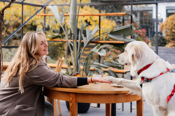 Woman and dog facing each other at cozy outdoor cafe table