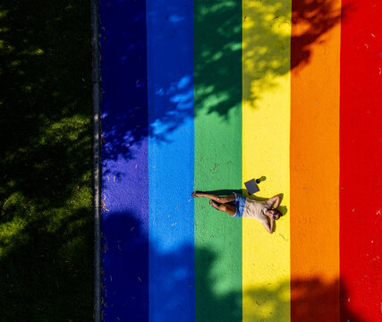 Aerial view of a person lies on a vibrant rainbow pride design, a spectrum of hope and acceptance amidst the city's green spaces, Melbourne, Victoria, Australia.