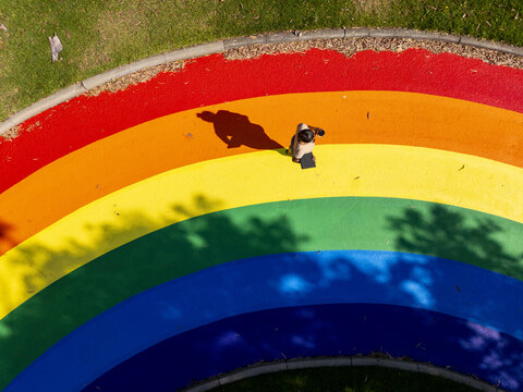 Aerial view of artistic rainbow pride paths in a public space, featuring a person walking on the rainbow walkway as a symbol of pride and social inclusion, Melbourne, Victoria, Australia.