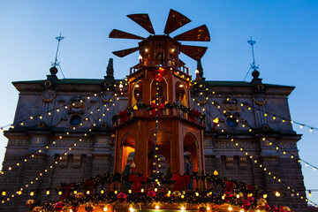 A festive structure stands decorated with lights and ornaments. The scene shows a lively market at dusk with the holiday spirit. Christmas market in Gdansk, Poland