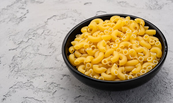 Raw macaroni pasta on stone table background	