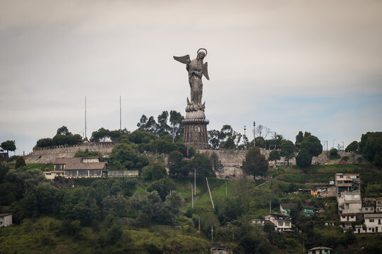 View of the iconic winged Virgin of Quito statue atop Panecillo Hill overlooking the city, a testament to faith against a cloudy sky, Quito, Ecuador.