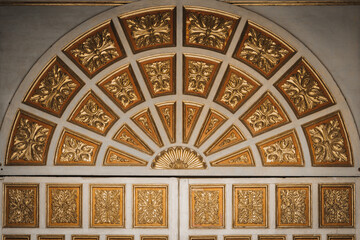 View of gilded floral carvings radiating in a semi-circular pattern above ornate panels, a rich display of craftsmanship, Quito, Ecuador.