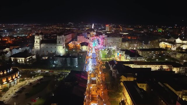 Drone night aerial of Stefan cel Mare boulevard Iasi Romania, illuminated ferries wheel and city town hall