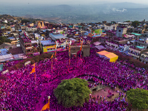 Aerial view of a sea of vibrant pink powder engulfing the temple and gathering crowds, a celebration of rich cultural heritage, Jyotiba Dongar, Maharashtra, India.