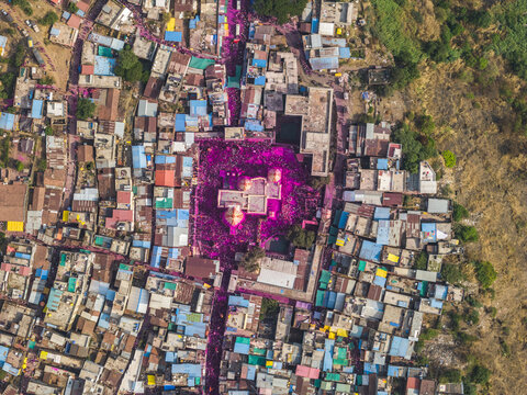 Aerial view of vibrant pink colors splashed across buildings and streets, creating a stunning contrast with the earthy tones of the landscape, Jyotiba Dongar, Maharashtra, India.
