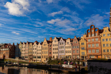 A row of buildings stands by the canal in Gdansk. A walk and enjoy the day under a blue sky with clouds.