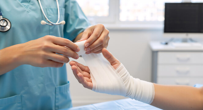 A healthcare professional carefully wrapping a bandage on a patient's injured hand. Medical treatment and first aid in a hospital clinic. - Powered by Adobe