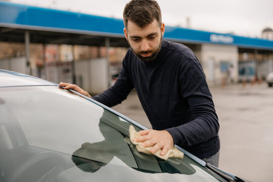 Man cleaning car glass with cloth during wash