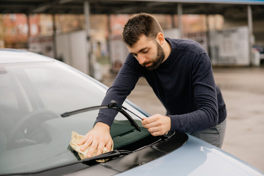 Car detailing process with worker wiping windshield