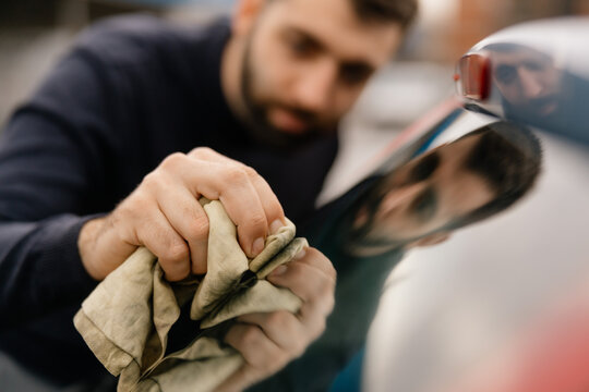 Man washing car windshield with cloth outdoors
