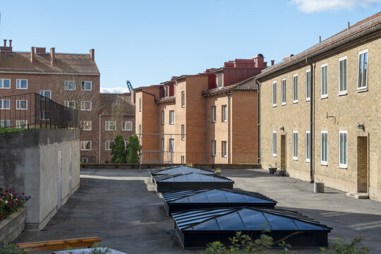 View of sunlight gleaming off the skylights, nestled between brick buildings beneath a serene blue sky, a quiet urban scene, Karlskrona, Blekinge County, Sweden.