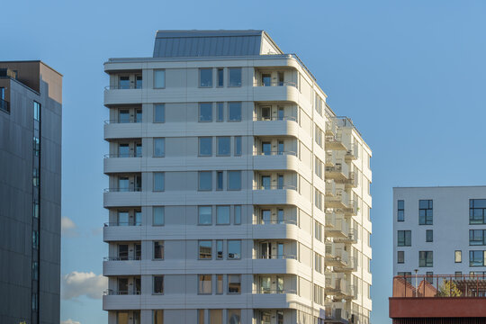 View of modern white building, its glass windows reflecting the clear sky, stands tall amidst urban architecture, Vastra Hamnen, Malmo, Sweden.