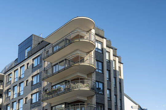 View of modern architecture featuring balconies with rounded edges and metal railings against a clear blue sky, Vastra Hamnen, Malmo, Sweden.