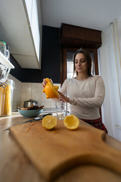 Woman squeezing fresh lemon juice in kitchen