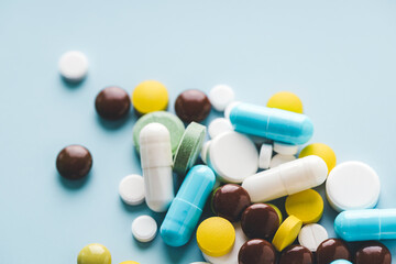 Various pills on blue background, angle view.