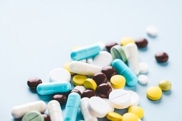 Various pills on blue background, angle view.