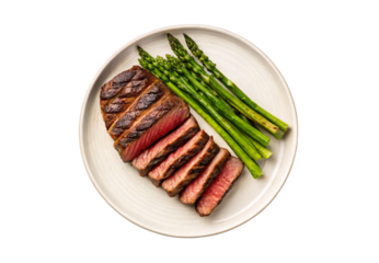 Sliced medium-rare ribeye steak with grilled asparagus on plate, isolated on a transparent background