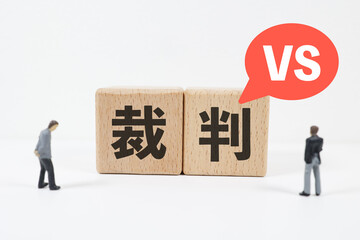 裁判を示す木製ブロックと対立する二人の男性ミニチュア人形