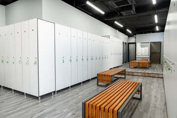 Modern gym locker room area with benches and secure lockers for personal belongings