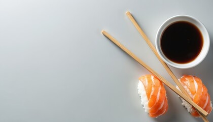 Two salmon nigiri sushi pieces with wooden chopsticks and a white bowl of soy sauce. Healthy Japanese food dish arranged neatly on a grey table. This Asian cuisine is ready for a delicious meal.