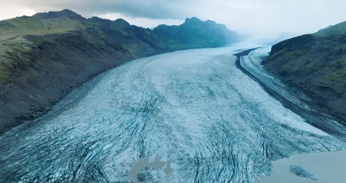 Aerial view of the majestic Skaftafell glacier, where icy blue textures meet rugged green mountains in a stunning display of Iceland's natural beauty, Skaftafell, Iceland.