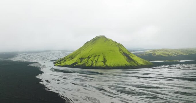 Aerial view of the verdant Maelifell mountain amidst the stark black volcanic landscape and braided glacial rivers, Maelifell, Iceland.