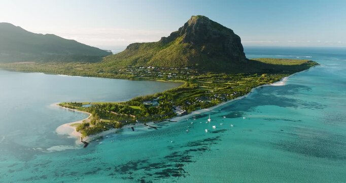 Aerial view of Le Morne Brabant's dramatic cliffs meet the turquoise waters, with boats dotting the coastline, creating a vibrant contrast, Le Morne, Mauritius.