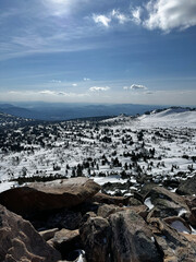Mountain view with snow and rocks under blue sky and bright sun.