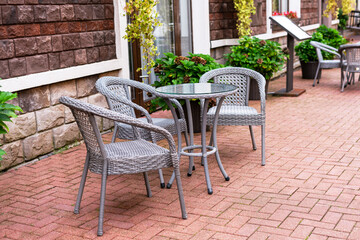 Outdoor cafe terrace with wicker chairs and table on a brick street, perfect city break vacation scene