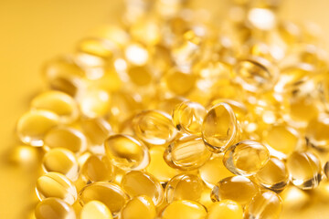 Closeup of fish oil softgels on yellow background. Suitable for: Omega 3, vitamin D, vitamin E, Omega 6, or Omega 9.