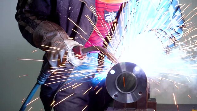 The worker welds steel parts with a semi-automatic welding machine