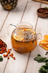 Aromatic sea buckthorn tea brewed with citrus slices herbs and spices served in a glass teapot on rustic table