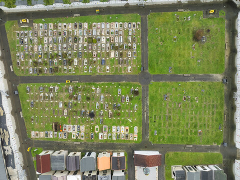 Aerial view of a serene cemetery where aged headstones stand amidst lush green plots, divided by pathways, creating a mosaic of life and memory, Serino, Irpinia, Campania, Italy.