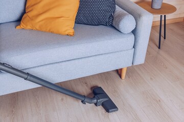 A Comfortable Living Room Scene Highlighting a Grey Couch with Cushions and a Vacuum Cleaner for Effortless Home Cleaning