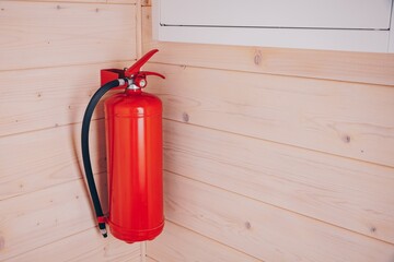 Bright Red Fire Extinguisher Mounted on a Wooden Wall in a Modern Interior Space for Fire Safety and Emergency Preparedness