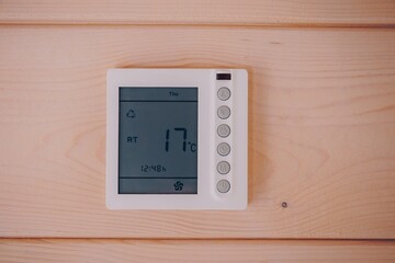 Digital Temperature Control Thermostat Displaying Current Room Temperature in a Cozy Wooden Environment