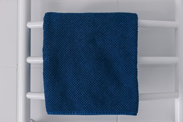 A Cozy, Deep Blue Towel Draped Elegantly on a Clean White Towel Rack in a Bright, Inviting Bathroom Setting