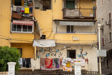 Mural and colorful laundry hanging in front of apartments in a building across from the Catacombs of Kos el Shoqafa in Alexandria, Egypt