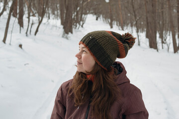 Smiling mid adult woman enjoys fresh air in winter snowy forest
