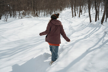 Smiling mid adult woman enjoys fresh air in winter snowy forest