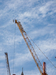 Construction crane with hook against blue sky and sunlight. Construction crane rises above a new building site under a bright blue sky Background Wallpaper