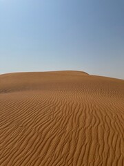 Minimal desert sand dune with rippled texture and blue sky