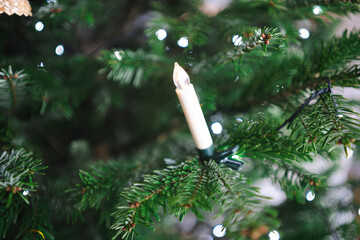 Lonely plastic Christmas candle hanging on tree with soft focus, minimal festive decoration detail