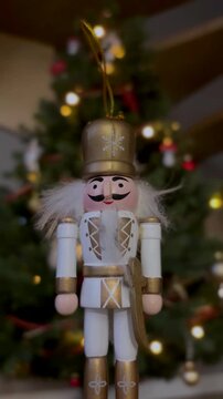 Nutcracker soldier on a Christmas tree. Seasonal toy figure before an illuminated artificial Christmas tree with lights and colorful decorations