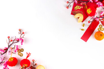 Bright vibrant gold and red Chinese New Year background with mandarin oranges, blossom tree branches, decorative fans, festive greeting envelops and coins, traditional Chinese New Year ornaments