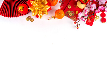 Bright vibrant gold and red Chinese New Year background with mandarin oranges, blossom tree branches, decorative fans, festive greeting envelops and coins, traditional Chinese New Year ornaments