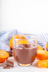 Sweet persimmon chocolate mousse, healthy vegan dessert with no added sugar, diet dessert food, with raw fresh persimmon fruit puree, chocolate or cocoa powder, on white kitchen table