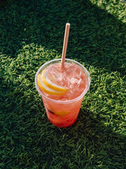 Iced Pink Lemonade with Straw on Green Grass